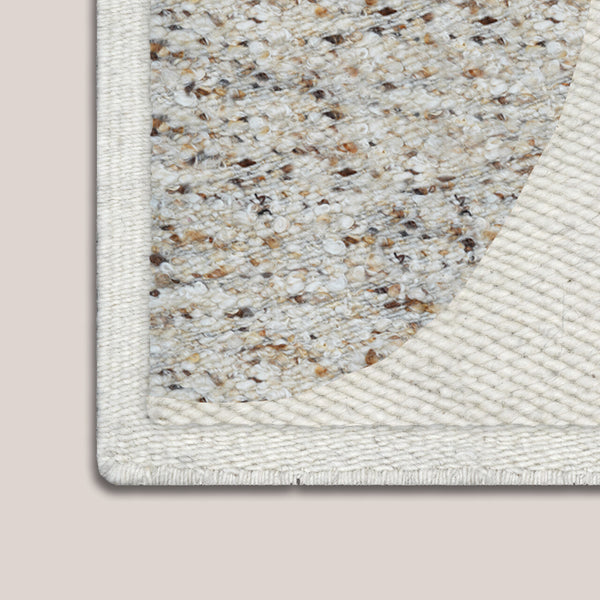 Close-up of a textured rug corner on a beige background